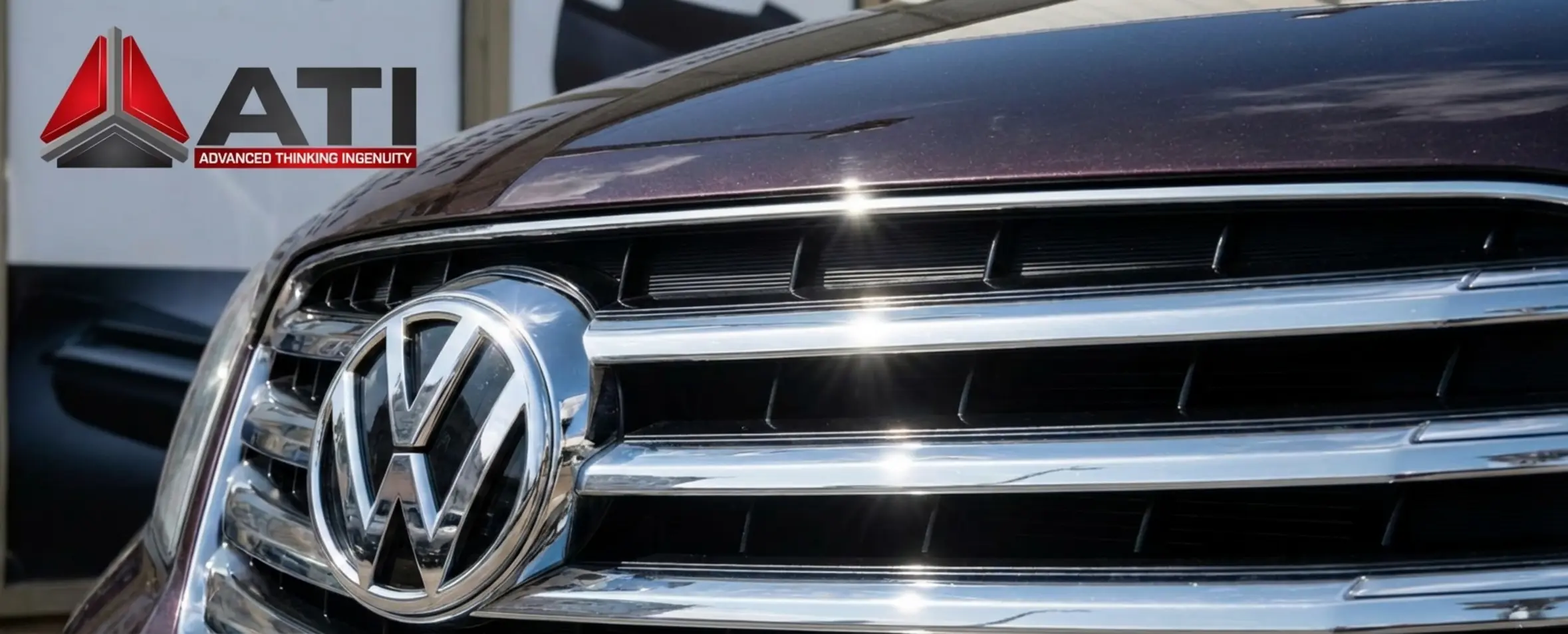 תמונה ברזולוציה גבוהה של חזית רכב יוקרה. הפוקוס הוא על הגריל הקדמי הנוצץ בציפוי כרום ועל סמל הרכב המבריק. השתקפות אור השמש על הגריל מדגישה את המראה המתכתי, למרות שברקע מוסבר שזהו בעצם חלק פלסטיק ABS מצופה.